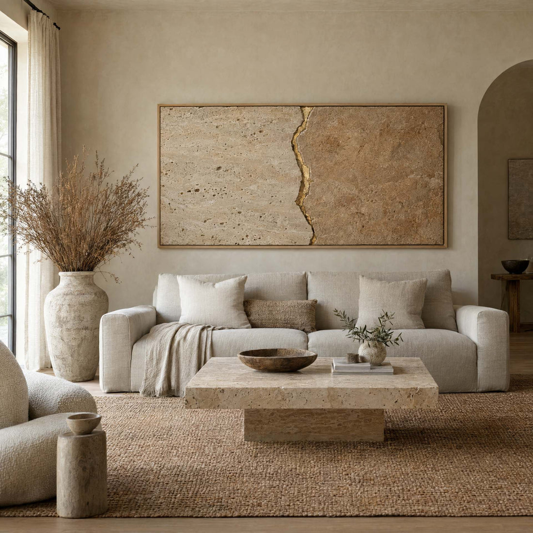 Cream travertine canvas with a gold kintsugi seam above a linen sofa