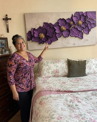 Customer pointing to a purple and gold floral canvas above her bed